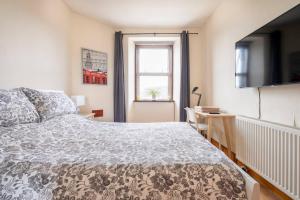 a bedroom with a bed and a television and a window at 2 Bed Central Ness Apart - May Court in Inverness