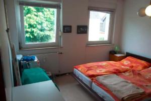 a small bedroom with a bed and two windows at Düsseldorf - separates, privates Zimmer in Düsseldorf