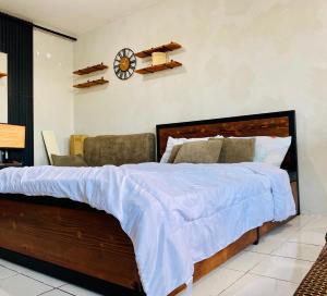 1 dormitorio con 1 cama grande y reloj en la pared en Casa Cabilao Staycation en Santa Rosa