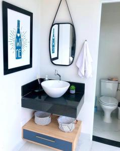 une salle de bain avec un lavabo et un miroir et des toilettes dans l'établissement Casa dos sonhos, relaxar Ninho Verde 1 com Piscina, à Quadra