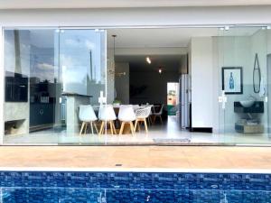 une cuisine et une salle à manger avec des parois et des chaises en verre dans l'établissement Casa dos sonhos, relaxar Ninho Verde 1 com Piscina, à Quadra