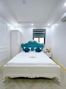 a bedroom with a large white bed with a blue headboard at Paris Hotel & Cafe in Vĩnh Long
