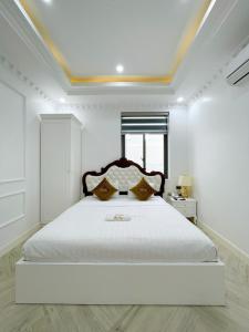 a white bedroom with a large white bed with a window at Paris Hotel & Cafe in Vĩnh Long