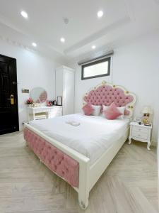 a bedroom with a large bed with a pink headboard at Paris Hotel & Cafe in Vĩnh Long
