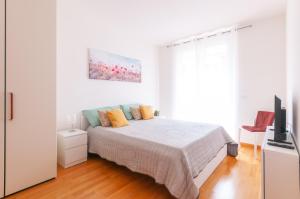 1 dormitorio blanco con 1 cama y TV de pantalla plana en DOR'MICHI', en Trento