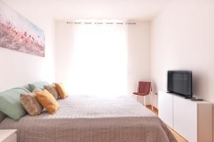 1 dormitorio blanco con 1 cama y TV en DOR'MICHI', en Trento