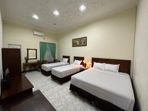 a hotel room with two beds and a desk at Hotel Winong Asri in Pati +14 photos