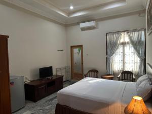 um quarto com uma cama, uma secretária e uma televisão em Hotel Winong Asri em Pati