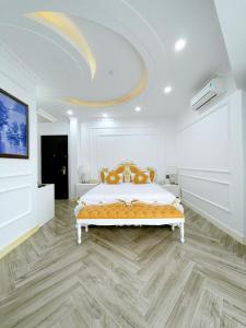 a large white bedroom with a bed with a yellow blanket at Paris Hotel & Cafe in Vĩnh Long