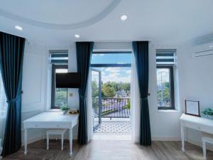 a room with two tables and a balcony with windows at Paris Hotel & Cafe in Vĩnh Long