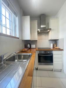 una cucina con armadi bianchi e un lavandino in acciaio inossidabile di Cozy Studio in Westminster a Londra