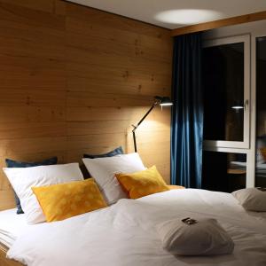 a bedroom with a large white bed with yellow pillows at Claudius Hotel in Bochum