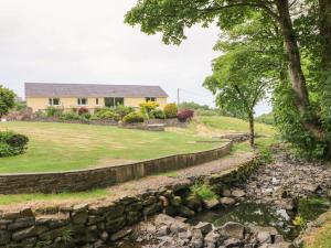 a house with a stone wall next to a river at Llety'r Bugail in Aberdare