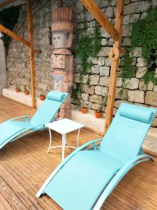 2 chaises et une table en face d'un mur en pierre dans l'établissement Hotel Restaurant Herard, à Bourbonne-les-Bains