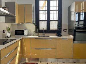 eine Küche mit gelben Schränken und einer Mikrowelle in der Unterkunft Casa Remanso de la Judería in Córdoba