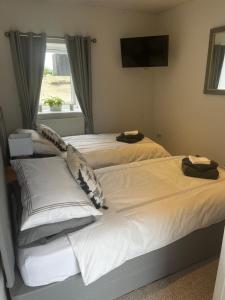 two beds in a bedroom with a tv on the wall at Lavender Cottage in Oundle
