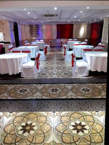 una sala banchetti con tavoli e sedie bianchi di Al Hedayet International Hotel a Seeb