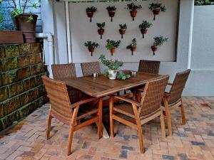 Four Palms Accommodation في دوربانفيل: طاولة خشبية مع كراسي وزخارف على الحائط