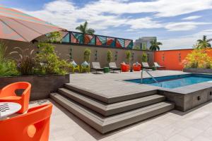 a patio with a pool and chairs and an umbrella at Aloft San Pedro Sula in San Pedro Sula