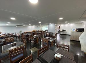 a restaurant with wooden tables and chairs and a person in the kitchen at Flat Praia de PontaNegra - Natal RN in Natal