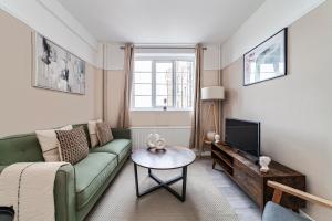 a living room with a green couch and a tv at The Crystal Palace Collection in London