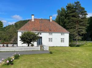 ein weißes Haus mit einem weißen Zaun im Hof in der Unterkunft Bosvik Gård, nyrenovert leilighet i hovedhus fra 1756 in Risør