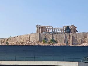 ein Gebäude vor einem Hügel mit einem Tempel in der Unterkunft Ulysses Apartments Acropolis in Athen