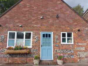 ein Backsteinhaus mit blauer Tür und zwei Fenstern in der Unterkunft Daisy Cottage in Child Okeford