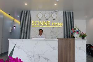 a man sitting at a reception desk in a hotel at Sonne Hotel Quang Binh in Ðộng Hỏi