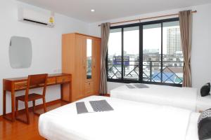 a room with two beds and a desk and a window at Double DD House at MRT Sutthisarn in Bangkok