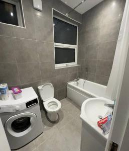 a bathroom with a toilet and a sink and a washing machine at Ground Flr 3-bed flat near Norbury Station in Norbury