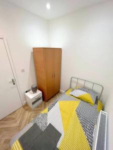 a bedroom with a bed and a wooden cabinet at Ground Flr 3-bed flat near Norbury Station in Norbury