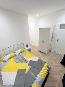 a bedroom with a bed with a yellow and gray blanket at Ground Flr 3-bed flat near Norbury Station in Norbury