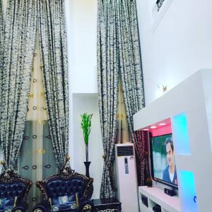 a living room with curtains and a tv at Mexiloyd Luxury Rooms & Suites in Port Harcourt