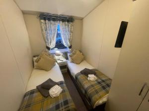 two beds in a small room with a window at Indulgence Lakeside Lodge i2 with hot tub, private fishing peg situated at Tattershall Lakes Country Park in Tattershall