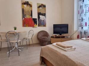 a bedroom with a bed and a tv and chairs at Home-Hotel Apartments on Maidan Nezalezhnosti Square in Kyiv
