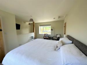 A lovely 1 bedroom annexe with kitchenette في Kidwelly: غرفة نوم بسرير ابيض كبير ونافذة