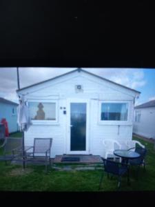uma casa branca com uma mesa e cadeiras num quintal em Karen's breakaway spot. em Leysdown-on-Sea