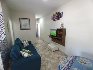 sala de estar con sofá azul y TV en Casa OliMar fins de semana, en Bertioga