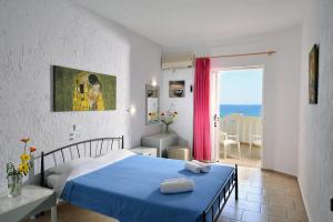 a bedroom with a blue bed and a view of the ocean at Arlen Beach Hotel in Hersonissos