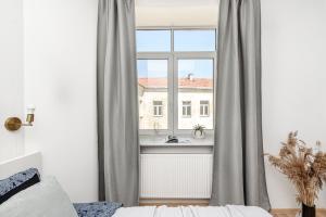 een slaapkamer met een raam met grijze gordijnen bij Spacious City Centre Apartment with Parking SELF CHECK-IN in Vilnius