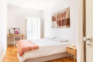 a white bedroom with a bed and a painting on the wall at Charming apartment by the river in Alcácer do Sal