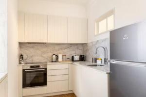 a kitchen with white cabinets and a stainless steel refrigerator at Charming apartment by the river in Alcácer do Sal