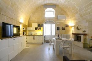 een keuken met een tafel met stoelen en een televisie bij Vivere nei Sassi in Matera