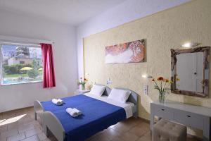 a bedroom with a white bed and a blue wall at Arlen Beach Hotel in Hersonissos