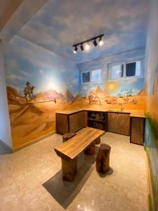 ein Zimmer mit einem Tisch und einem Wandbild einer Wüste in der Unterkunft The New House in Ấp Ða Lợi