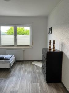 um quarto com uma cama, uma cómoda e 2 janelas em F&M Wohnungen in Olpe em Olpe