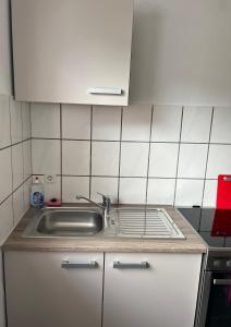 cocina con fregadero y paredes de azulejos blancos en F&M Wohnungen in Olpe, en Olpe