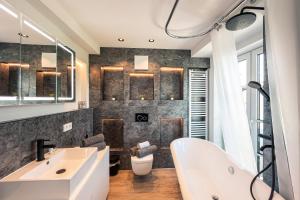 uma casa de banho com uma banheira branca e um lavatório. em CREST - Riverside Lofts mit Whirlpool & Wanne I Parken I Balkon I Netflix I Küche em Passau
