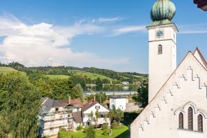 a church with a clock tower in a village at CREST - Riverside Lofts mit Whirlpool & Wanne I Parken I Balkon I Netflix I Küche in Passau